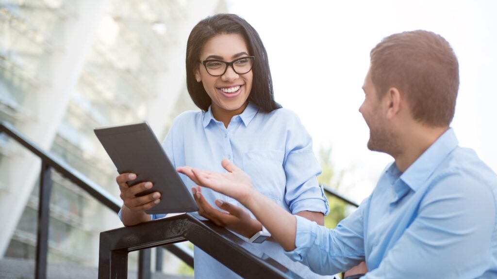 Two professionals discussing study materials, one holding a tablet, highlighting a collaborative learning environment for exam preparation.