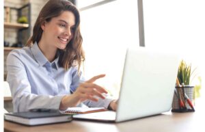 woman sitting at desk using laptop and smiling